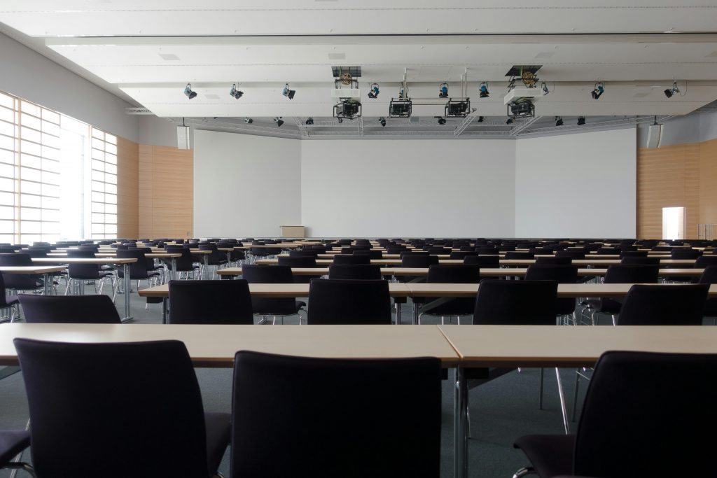 hall-congress-architecture-building-159213-159213 Spacious contemporary conference room with rows of tables and chairs, ready for meetings.