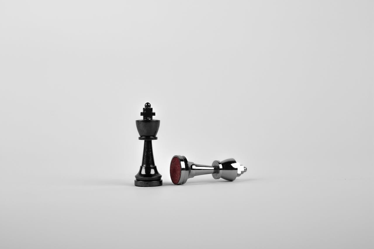about-us Close-up of chess king piece standing with a fallen piece symbolizing strategy and victory.